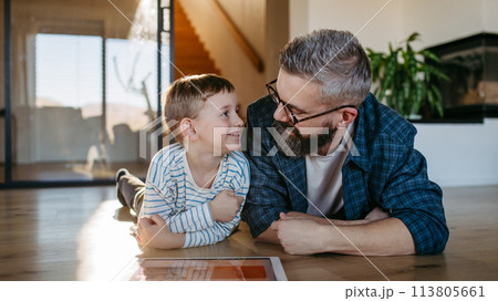 Father showing son smart home system, adjusting household functions, lighting, security cameras, door locks and smart thermostat or heating settings. Concept of sustainable and smart technology in 113805661