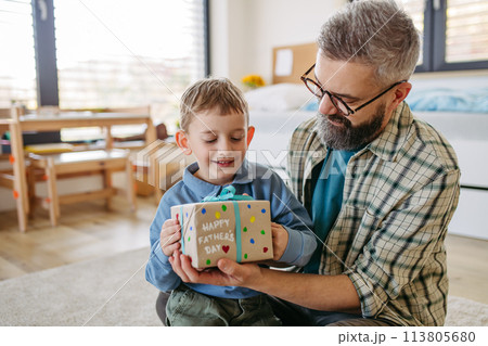 Dad get a handmade gift from little son, present wrapped in diy homemade wrapping paper. Happy Fathers day concept. Dad get a handmade gift from little son, present wrapped in diy homemade wrapping paper. Happy Fathers day concept. 113805680