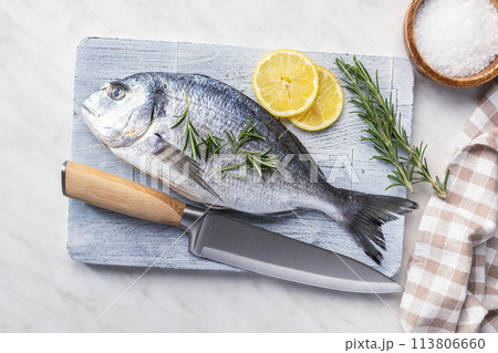 Fresh sea bream fish on cutting board on kitchen table. Top view. Fresh sea bream fish on cutting board on kitchen table. Top view. 113806660