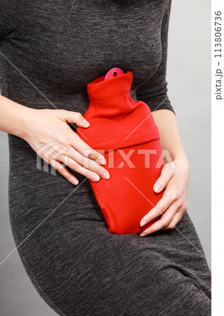 Girl having stomach ache, holding hot water bottle 113806736