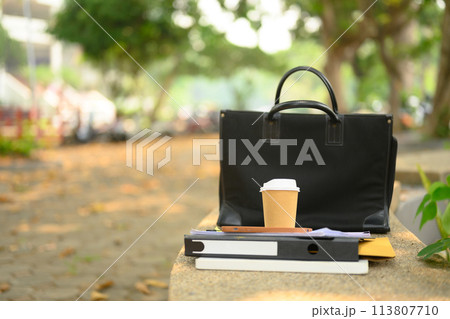 Closeup of briefcase, takeaway coffee cup and document on concrete bench. City life concept 113807710