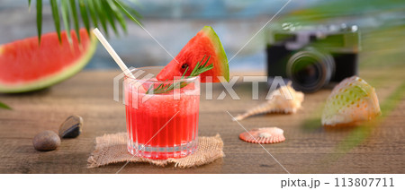 Fresh watermelon juice, seashells and camera on wooden table. Summer vacation and travel concept Fresh watermelon juice, seashells and camera on wooden table. Summer vacation and travel concept 113807711