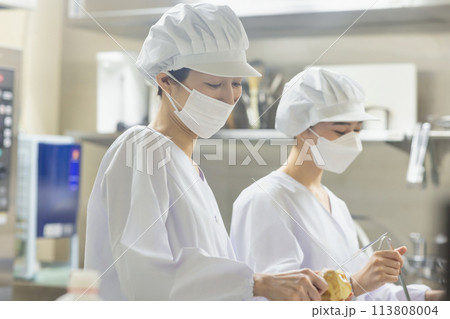 白衣を着て食事を作る女性 113808004