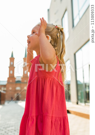 Child with hearing problem and cochlear implant dance in street, deaf kid began to hear. Hearing loss in childhood and treatment concept. Inclusion and disability 113809333