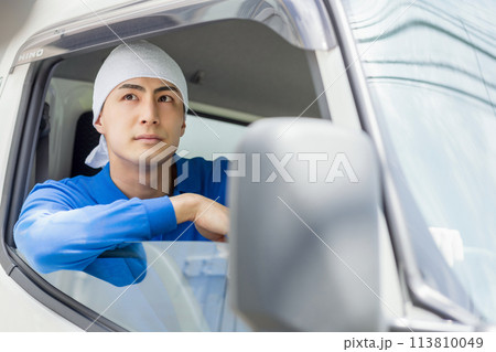 トラックを運転する若い男性 113810049