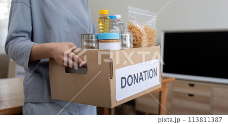Woman volunteer holding food donation box at home Woman volunteer holding food donation box at home 113811387