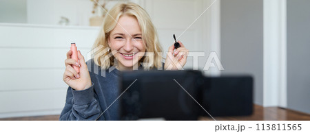 Portrait of beauty blogger, woman records video on camera in her room, shows makeup beauty products, talks about cosmetics in vlog, makes lifestyle content for followers on social media 113811565