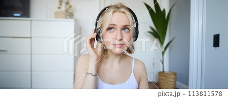 Concept of people and lifestyle, Close up of beautiful blond woman in wireless headphones, listens to music, enjoys good quality sound in new earphones 113811578