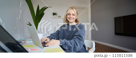 Portrait of young woman, student studying at home on remote education, working on laptop, typing on keyboard Portrait of young woman, student studying at home on remote education, working on laptop, typing on keyboard 113811586