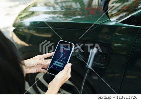 Woman controlling electric car charging level via mobile app 113811726