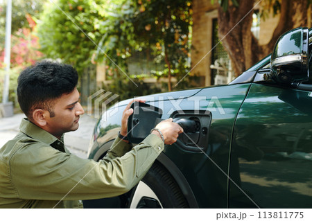 Indian electric car owner charging his vehicle 113811775