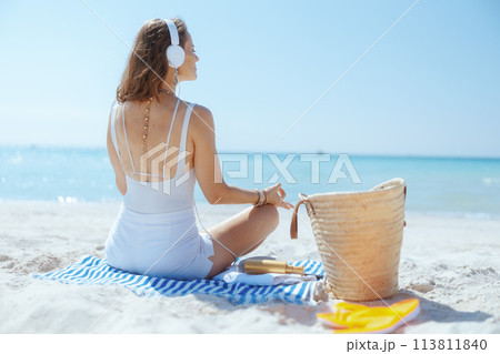 elegant 40 years old woman on seashore listening to music elegant 40 years old woman on seashore listening to music 113811840