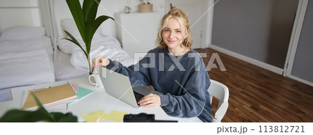 Portrait of woman sitting at desk with laptop, recording video of herself on laptop, making lifestyle video for social media account Portrait of woman sitting at desk with laptop, recording video of herself on laptop, making lifestyle video for social media account 113812721