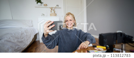 Portrait of young woman, girl beauty blogger, recording vlog in her bedroom, doing makeup tutorial for social media followers, taking selfies, live streaming on mobile phone app 113812783