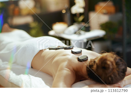 woman having hot stone massage and laying on massage table woman having hot stone massage and laying on massage table 113812790
