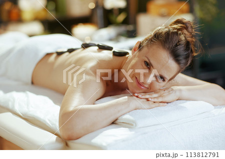 woman having hot stone massage and laying on massage table 113812791