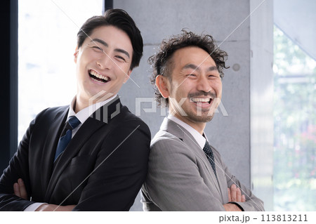 スーツを着て腕組みで背中合わせで見上げるビジネスマンたち　目標や未来を見つめるイメージ 113813211
