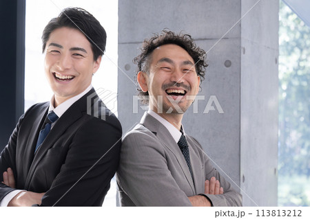 スーツを着て腕組みで背中合わせで大笑いで見上げるビジネスマンたち　目標や未来を見つめるエクゼクティブ 113813212