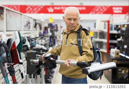 Senor man pensioner buying Upright Vacuum Cleaner in showroom of electrical appliance store 113813261