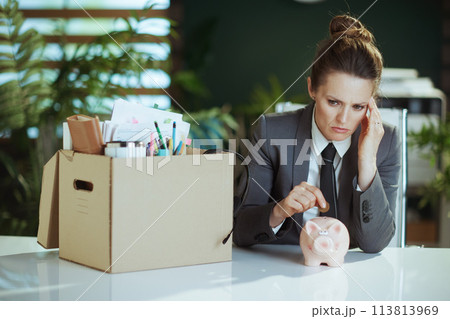 woman worker in green office putting coin into piggy bank 113813969