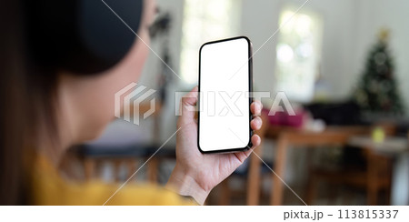 Mockup smartphone of a woman holding mobile phone with blank white screen while sitting listen to music at home Mockup smartphone of a woman holding mobile phone with blank white screen while sitting listen to music at home 113815337