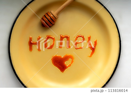 Honey spindle, inscription and heart on yellow plate. Dark grade. Top view Honey spindle, inscription and heart on yellow plate. Dark grade. Top view 113816014