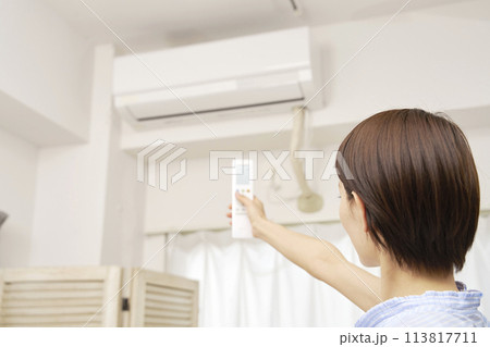 エアコンのリモコンを使う女性 113817711