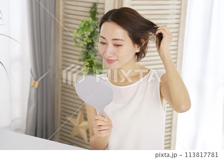 髪の毛を鏡で確認する中年女性 113817781