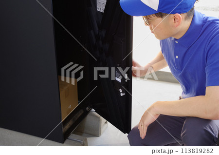 宅配ボックスに荷物を入れる配達員 113819282