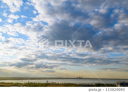 CHP and other plants stand on the shore of the lake in the evening under clouds in the sky 113820093