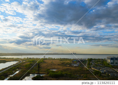 Picturesque scenery with a field and a lake under clouds at sunset Picturesque scenery with a field and a lake under clouds at sunset 113820111