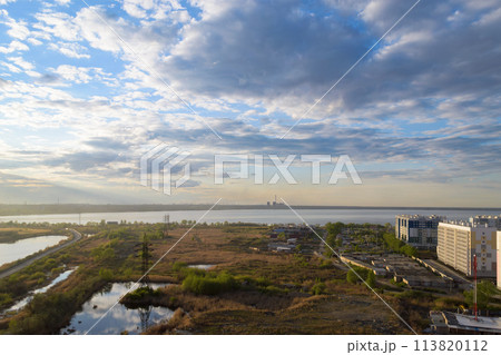 Picturesque scenery with a field and a lake under clouds at sunset 113820112