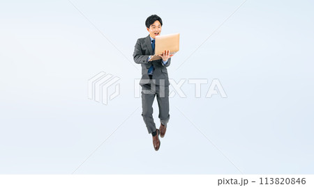 ノートパソコンを見ながらジャンプする男性ビジネスパーソンの全身写真 113820846