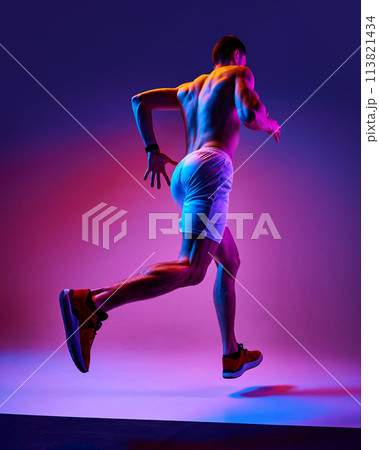 Bottom view of muscular, athletic young man training shirtless, running on gradient pink purple background in neon light Bottom view of muscular, athletic young man training shirtless, running on gradient pink purple background in neon light 113821434