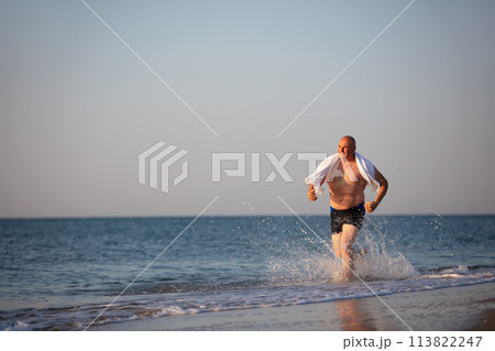 An elderly man runs along the beach. An elderly man runs along the beach. 113822247