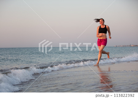 A middle-aged woman jogging along the coast. Sports at sea adult woman. 113822392