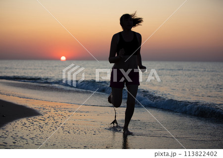Silhouette of a woman athlete on a background of sunrise at sea Silhouette of a woman athlete on a background of sunrise at sea 113822402