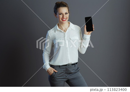 business woman showing smartphone blank screen isolated on gray business woman showing smartphone blank screen isolated on gray 113823400