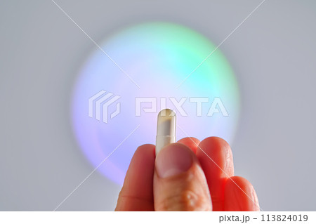 Capsule in hand against the background of a glowing circle. 113824019