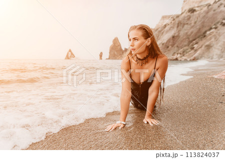 Woman summer travel sea. Happy tourist in black dress enjoy taking picture outdoors for memories. Woman traveler posing on sea beach surrounded by volcanic mountains, sharing travel adventure journey 113824037