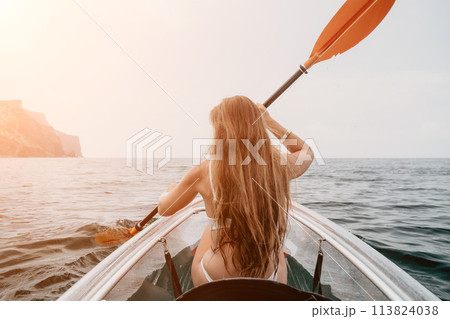 Woman in kayak back view. Happy young woman with long hair floating in transparent kayak on the crystal clear sea. Summer holiday vacation and cheerful female people relaxing having fun on the boat Woman in kayak back view. Happy young woman with long hair floating in transparent kayak on the crystal clear sea. Summer holiday vacation and cheerful female people relaxing having fun on the boat 113824038