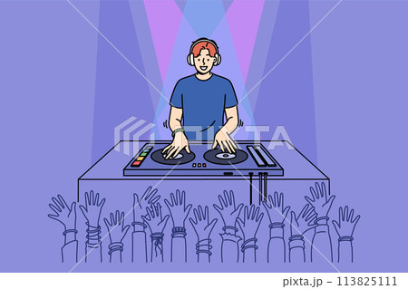 Man DJ performs in nightclub spinning records on mixing console, near partygoers hands 113825111