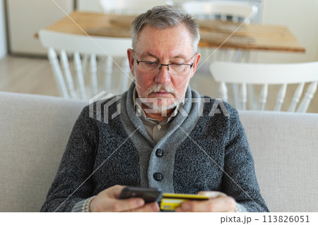 Senior man shopping online holding smartphone paying with credit card. Old grandfather buying on Internet enter credit card details. Online shopping delivery service Older generation modern tech usage Senior man shopping online holding smartphone paying with credit card. Old grandfather buying on Internet enter credit card details. Online shopping delivery service Older generation modern tech usage 113826051
