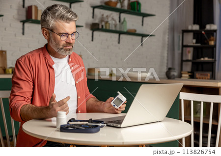 Online medical consultation for diabetic patient man with glucometer via laptop 113826754