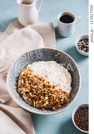 Granola with nuts in a bowl with classic yogurt for healthy eating on the table vertical view Granola with nuts in a bowl with classic yogurt for healthy eating on the table vertical view 113827492