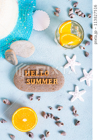Hello summer text on stone, hat, cocktail, orange, starfish and seashells on blue top and vertical 113827516