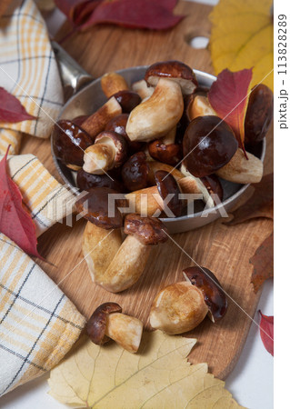 Several Imleria Badia or Boletus badius mushrooms commonly known as the bay bolete and vintage pan with mushrooms on wooden cutting board.. 113828289