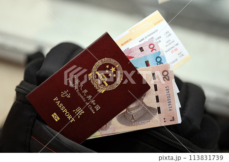 Red passport of People Republic of China and chinese yuan money bills with airline tickets on backpack close up. PRC passport Red passport of People Republic of China and chinese yuan money bills with airline tickets on backpack close up. PRC passport 113831739