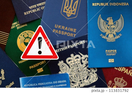 Many various passports of citizens of different countries and regions of the world and alert sign close up 113831792