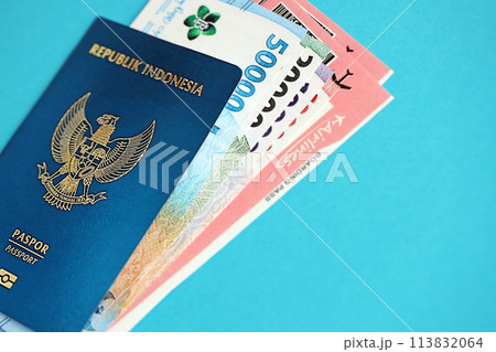 Blue Republic Indonesia passport with money and airline tickets on blue background close up. Tourism and travel concept Blue Republic Indonesia passport with money and airline tickets on blue background close up. Tourism and travel concept 113832064